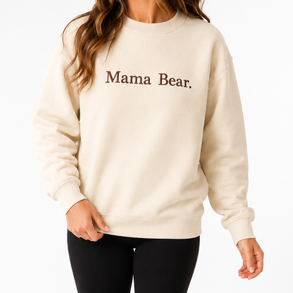 Woman wearing a cream sweatshirt with 'Mama Bear' text on a white background